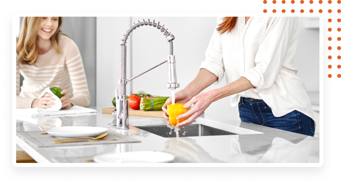 Mother and daughter washing food in the sink.