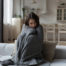 Unhappy girl wrapped in a blanket due to the house being cold